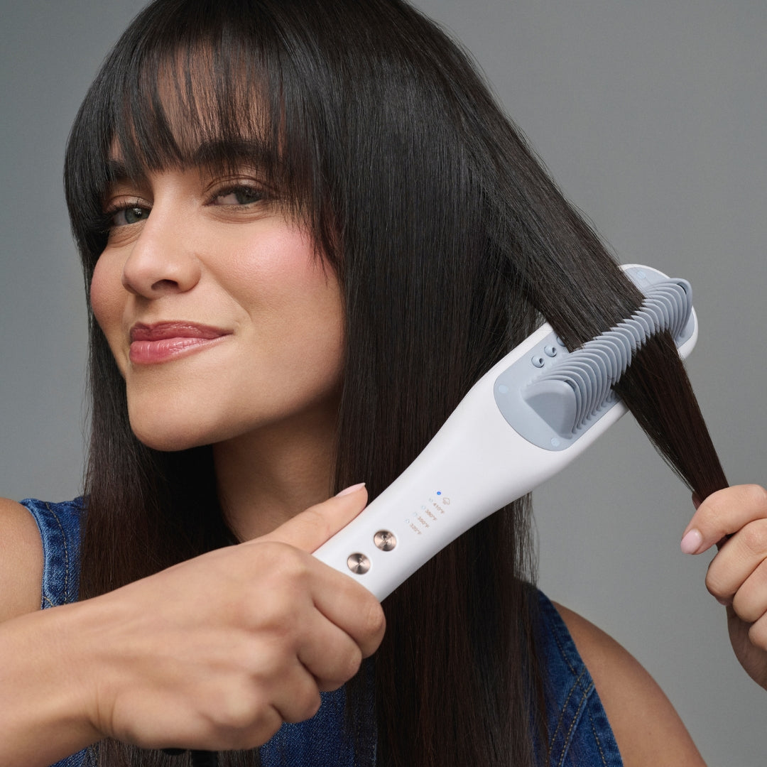 Woman using a white steamline pro iron on her hair against a gray background