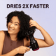 Black Blown Away hair dryer held by a woman, featuring the text "Dries 2X Faster" against a light purple background.