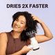 White Blown Away hair dryer held by a woman, featuring the text "Dries 2X Faster" against a light purple background.