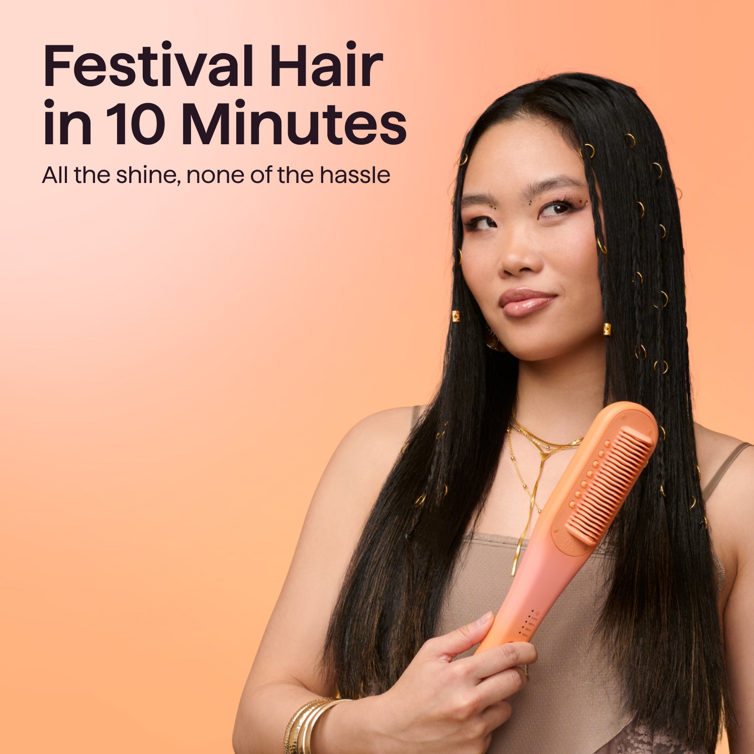 Woman holding an orange electric hair straightening brush, featuring styled long black hair with gold rings. Text reads "Festival Hair in 10 Minutes.