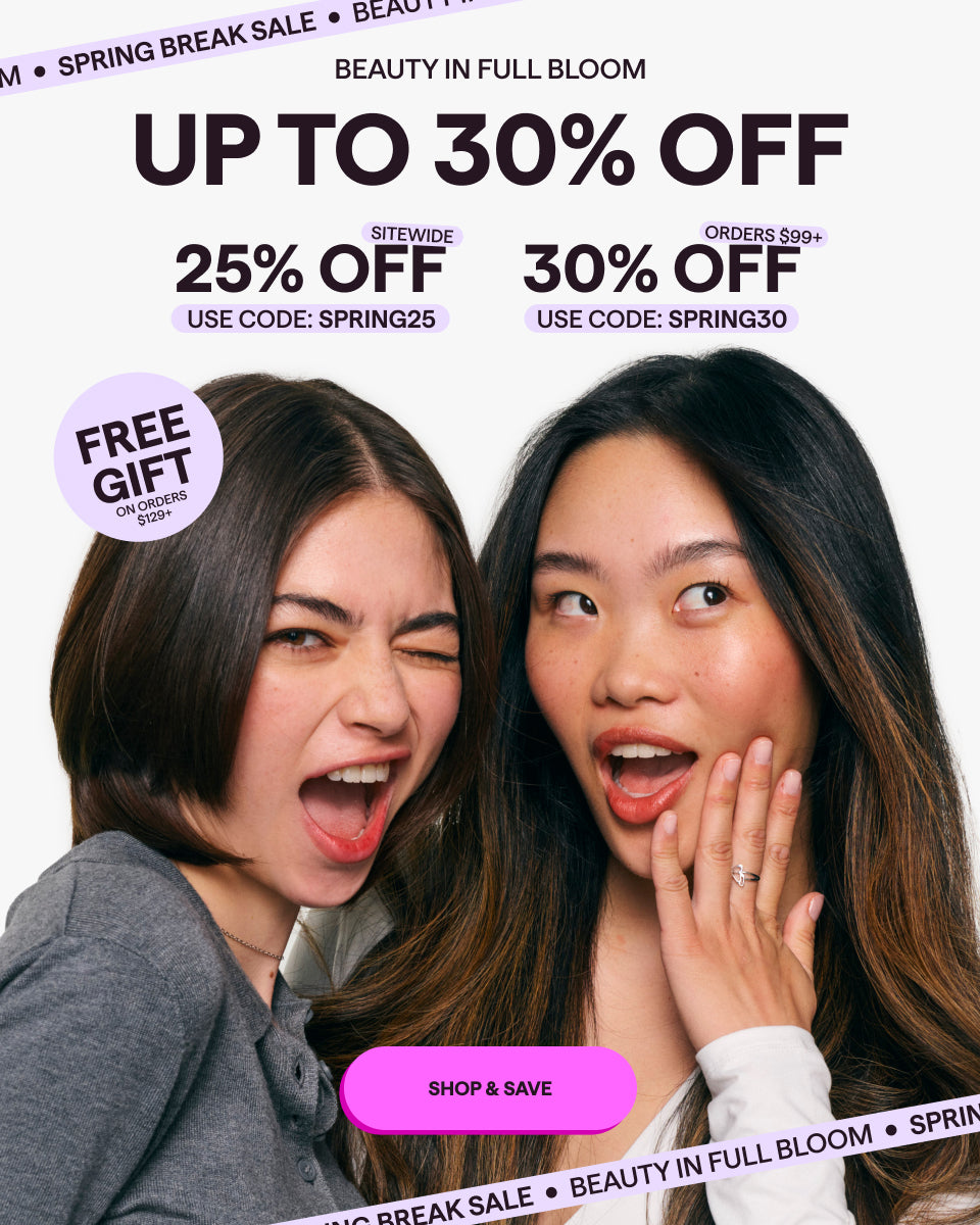 Two women with a promotional banner for a beauty sale with discounts and a free gift offer.